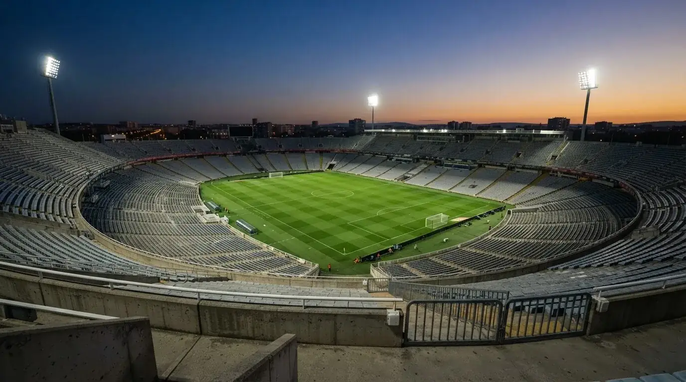 Een leeg voetbalstadion met lichtmasten bij schemering